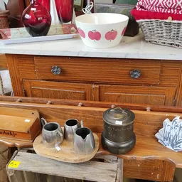 Houten display met vintage servies- en huishoudartikelen, inclusief zilveren kannen en decoratieve pot