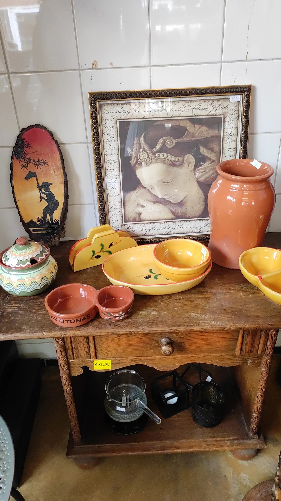 Uitgestalde vintage serviesgoed op houten tafel: gele en oranje keramische schalen, rode potjes en decoratieve items