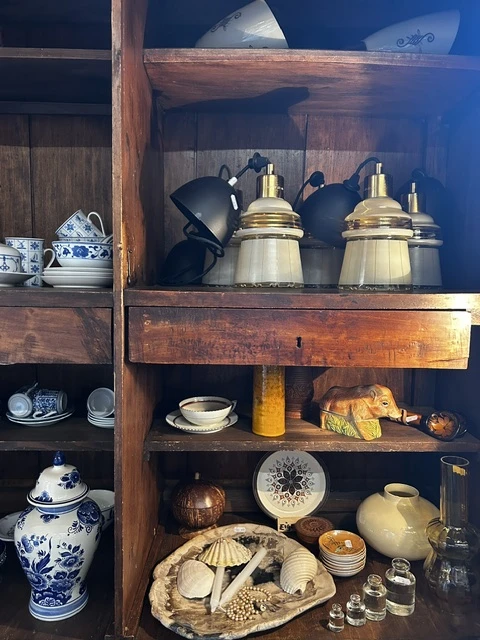 Houten kastje met vintage serviesgoed, koppelingen, pannen en decoratieve items netjes uitgestald