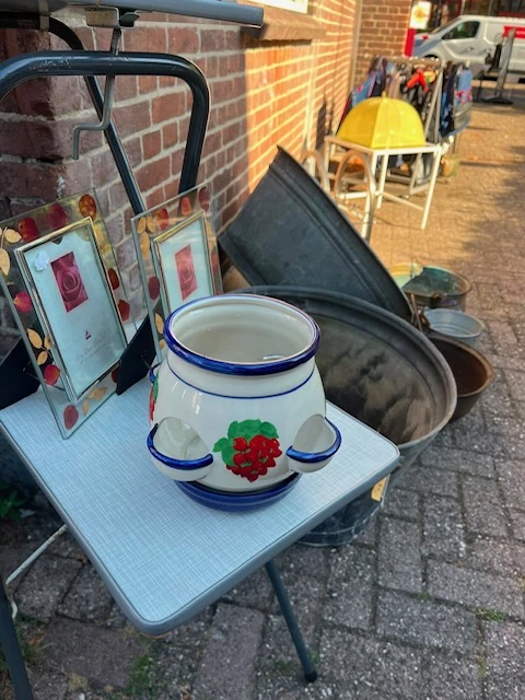 Witte porseleinen pot met blauwe rand en rode roosdecoratie op display