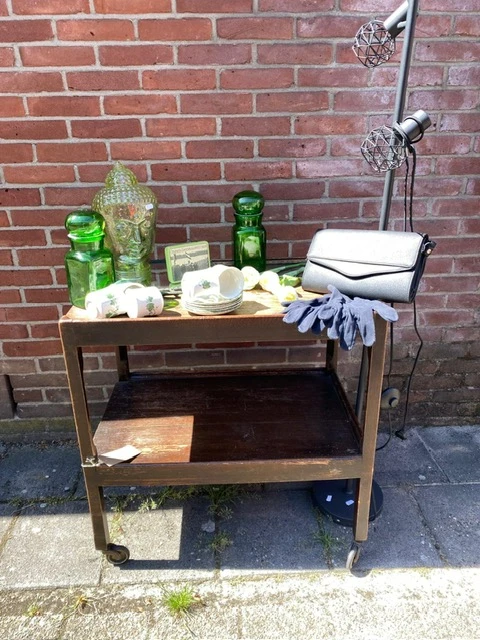 Tafel met huishoudelijke spullen: glazen flessen, servies, handdoeken en papieren rollen