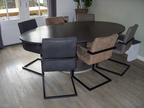 Ronde eettafel met zwart blad en zwarte metalen stoelen met beige en grijze bekleding