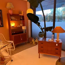 Vintage interieur met houten meubels, oranje wandkleur, raamvista op water, retro lampenkap en decoratieve objecten