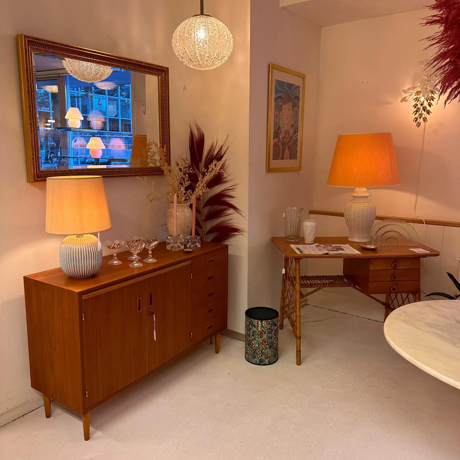 Vintage woonkamervignette met houten dressoir, lamp, tv-frame aan muur, bloemstuk en houten bijzettafel met lamp