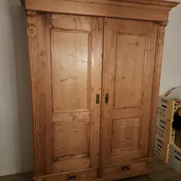 Houten kast met twee deuren en decoratieve ornamenten, gemaakt van grenen met natuurlijke nerfstructuur