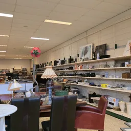 Winkelvloer met zithoeken, rekken vol elektronicaartikelen en decoratieve items tegen de muur