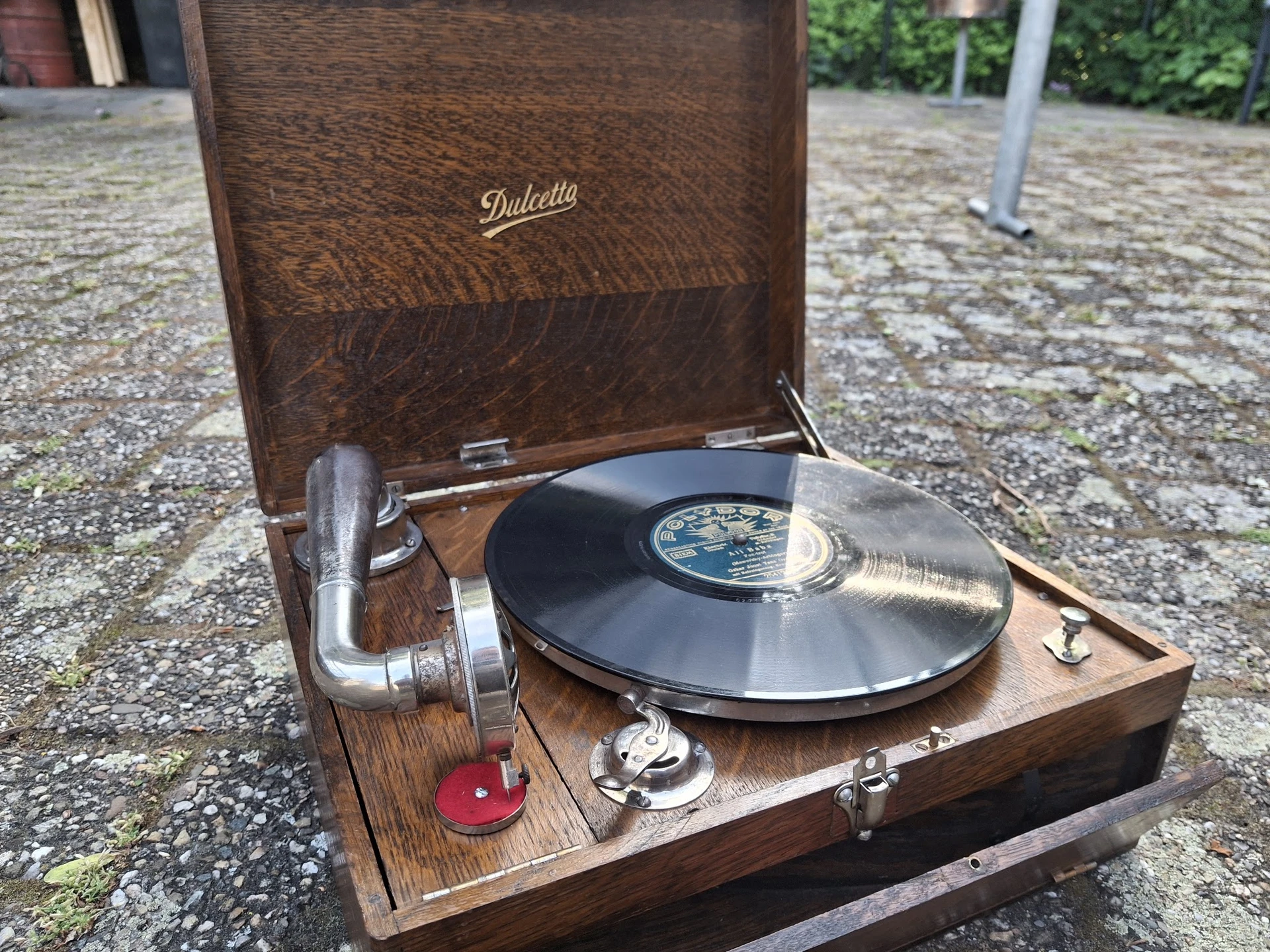 Vintage grammofoon met houten kast en zwart vinyl record, buiten gefotografeerd