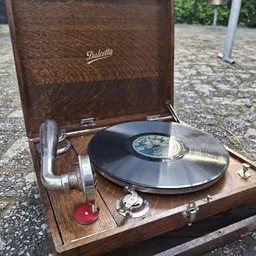 Vintage grammofoon met houten kast en zwart vinyl record, buiten gefotografeerd
