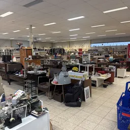 Ruim winkelinterieur met diverse meubels, huishoudelijke artikelen en spullen uitgestald op tafels en stellingen