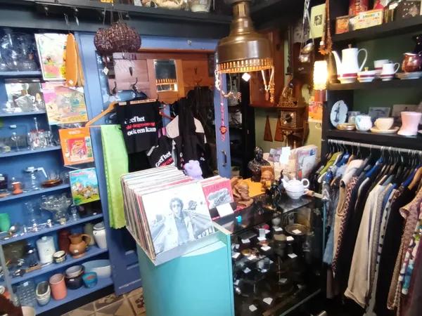 Winkelvloer van kringloopwinkel met stellingen, kledingrekken, vintage artikelen en decoraties