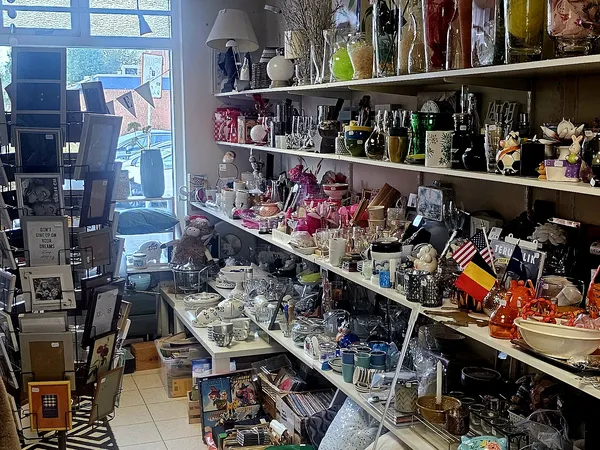 Glazen vitrines en wandrekken met diverse tweedehands artikelen, decoratie en verzamelobjecten in kringloopwinkel