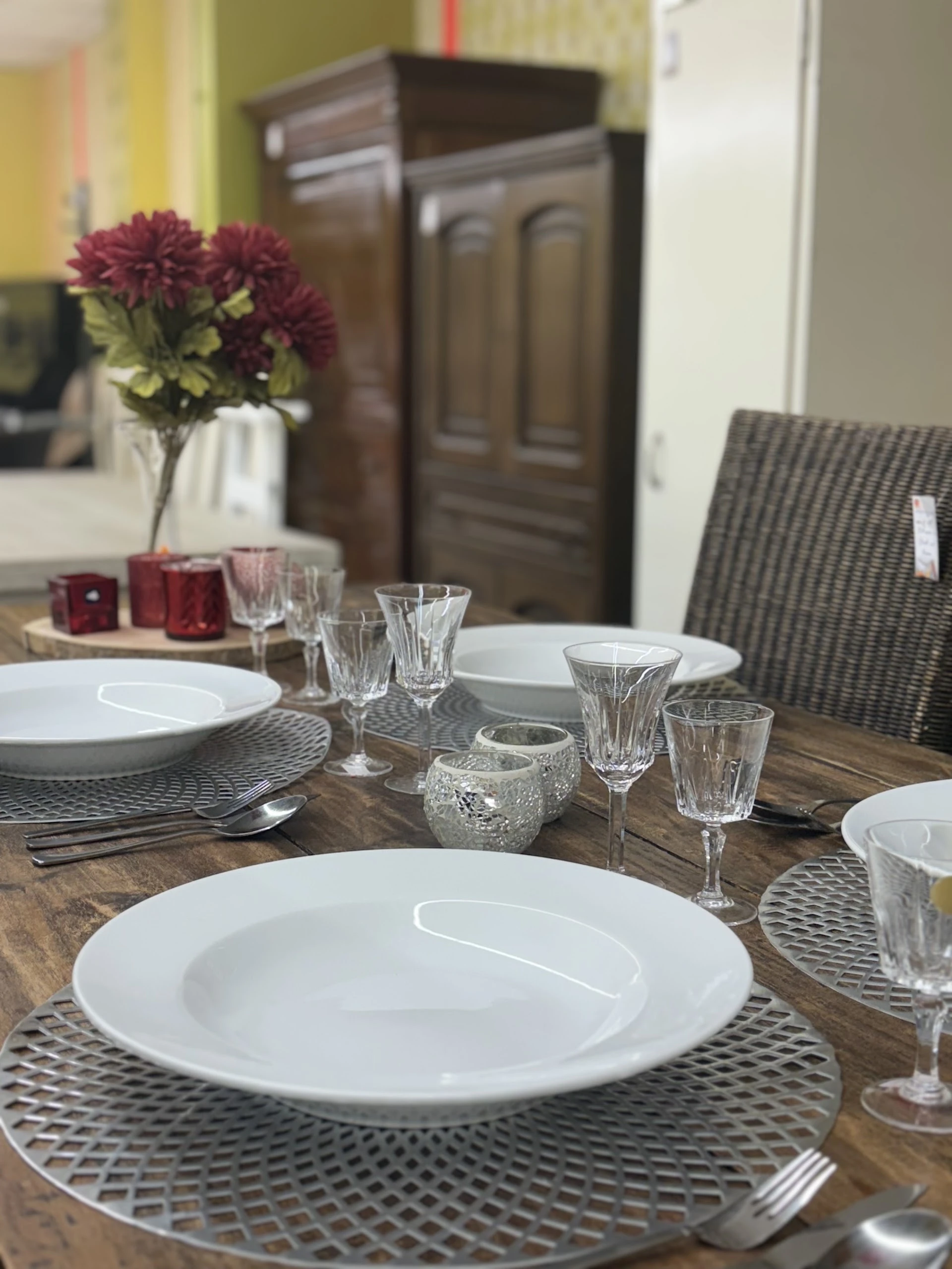 Gedekte eettafel met witte borden, kristallen glazen en bloemenvaas in een ingerichte ruimte