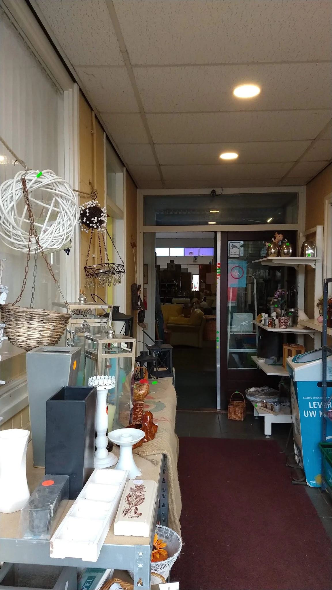 Winkelvloer met decoratieve items, planken met spullen en uitzicht naar het verkoopgedeelte