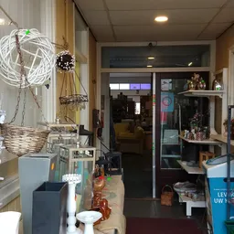Winkelvloer met decoratieve items, planken met spullen en uitzicht naar het verkoopgedeelte