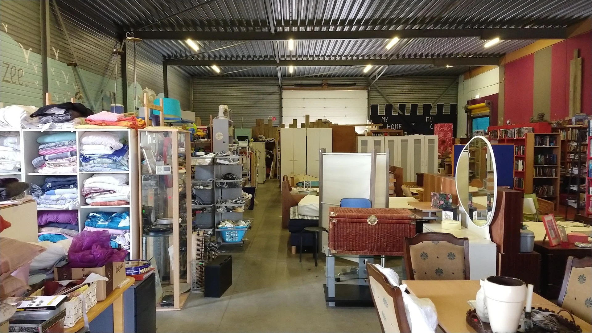 Winkelvloer van kringloopwinkel met diverse meubels, huishoudelijke artikelen en rekken met spullen