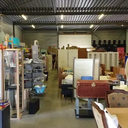 Winkelvloer van kringloopwinkel met diverse meubels, huishoudelijke artikelen en rekken met spullen