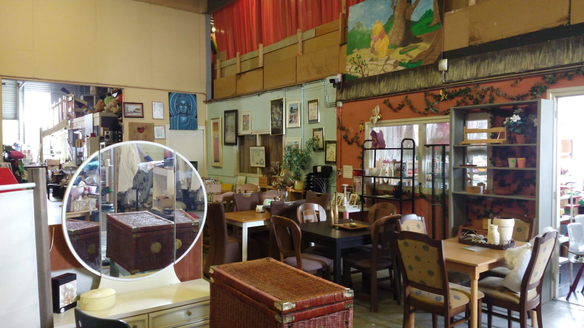 Interieur van kringloopwinkel met meubels, kunstwerken aan muren en diverse spullen in verschillende hoeken