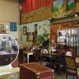 Interieur van kringloopwinkel met meubels, kunstwerken aan muren en diverse spullen in verschillende hoeken