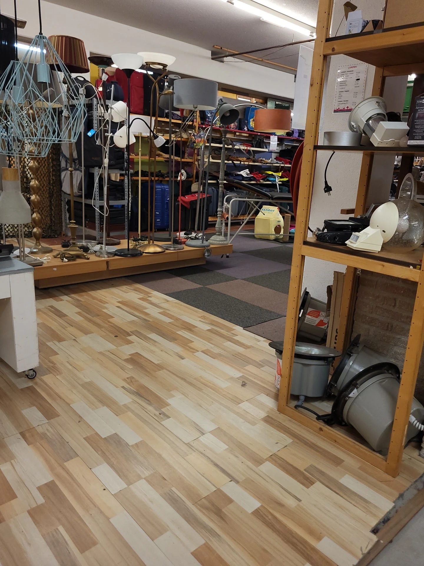 Winkelinterieur met houten vloer, stellingen met artikelen en diverse spullen verspreid in de ruimte