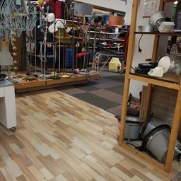 Winkelinterieur met houten vloer, stellingen met artikelen en diverse spullen verspreid in de ruimte