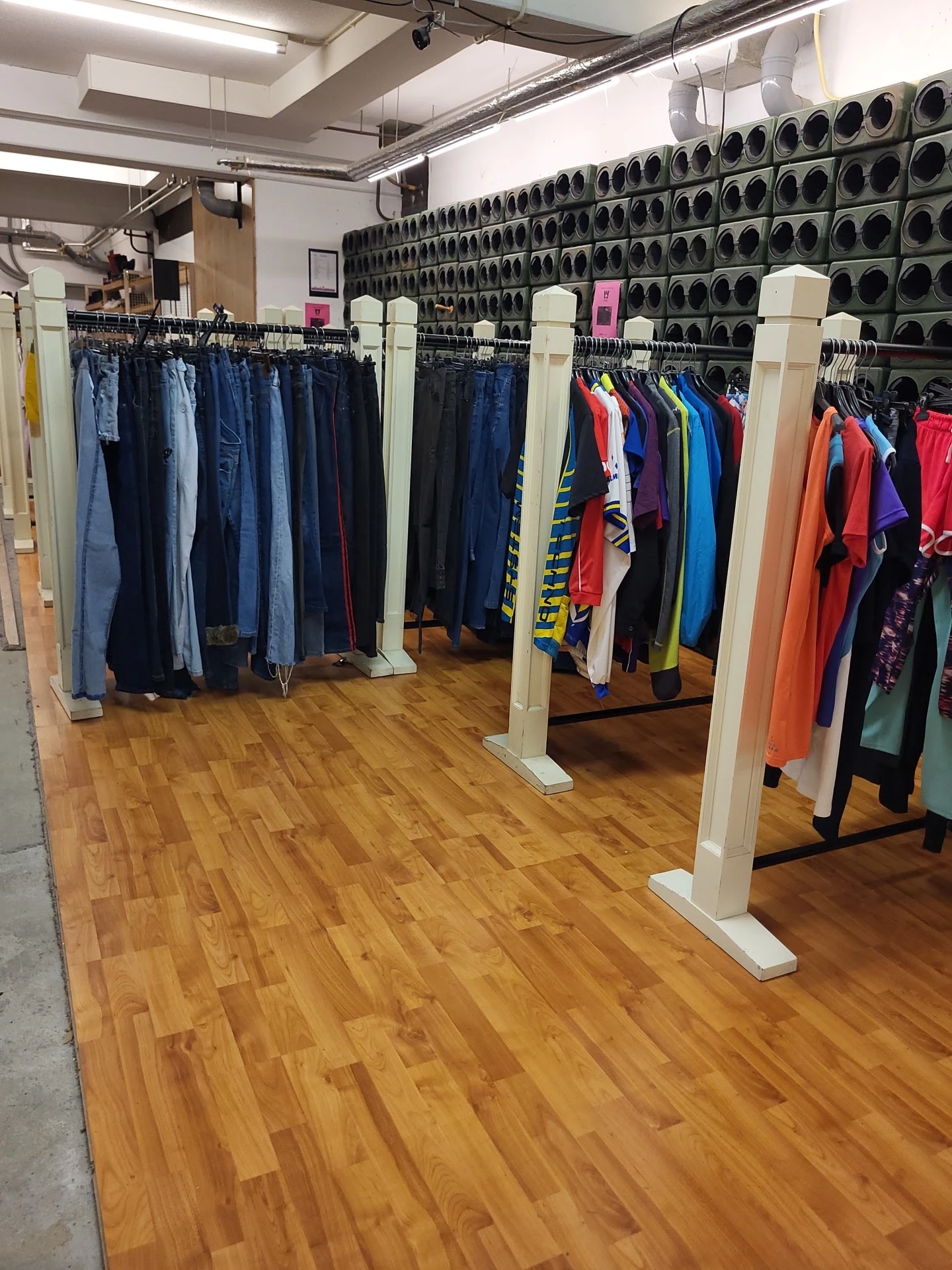 Rekken met tweedehands kleding in diverse kleuren en stijlen in de winkel
