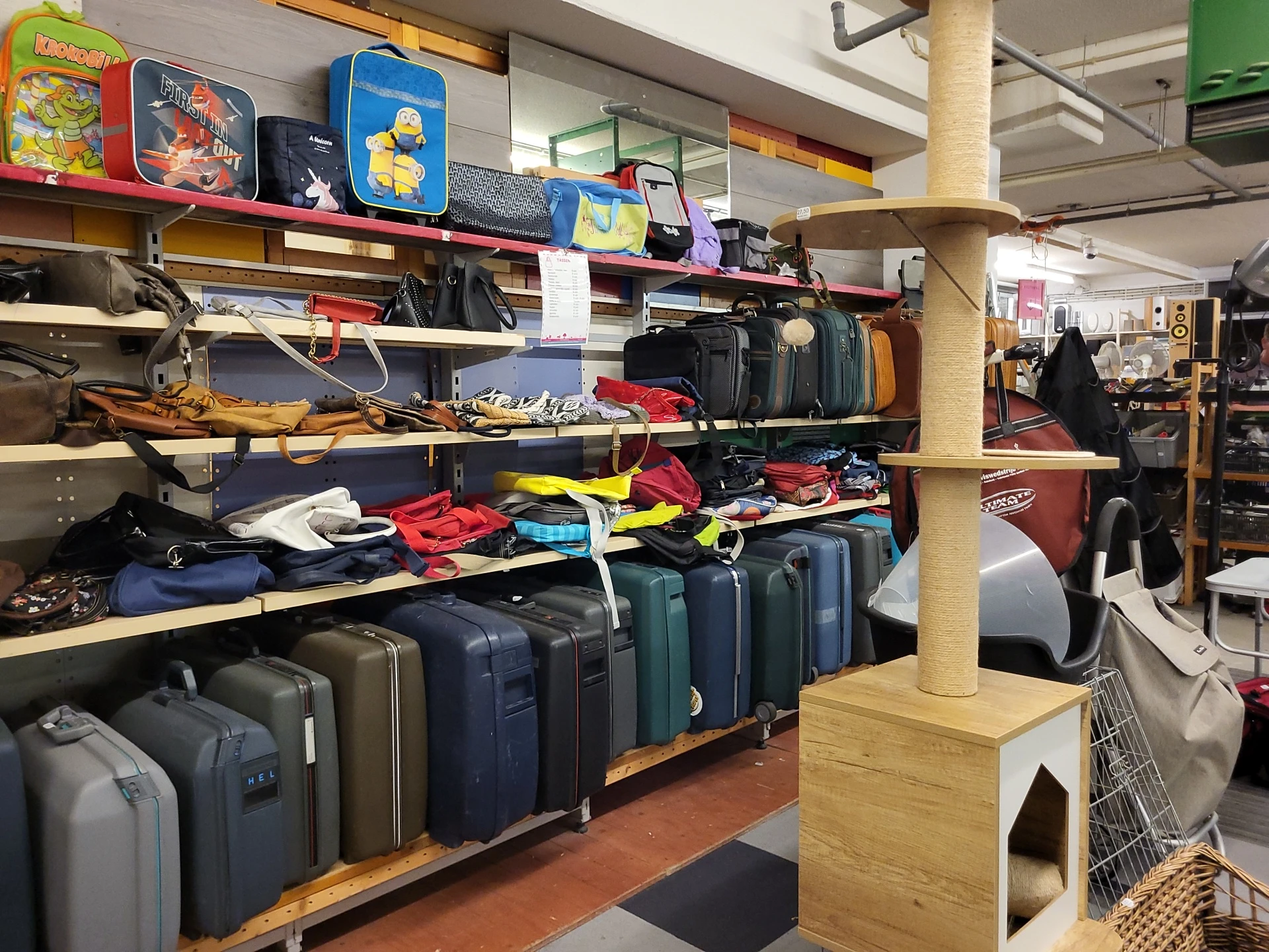 Schappen en rekken vol met tweedehands koffers, tassen en reisartikelen in verschillende kleuren en maten
