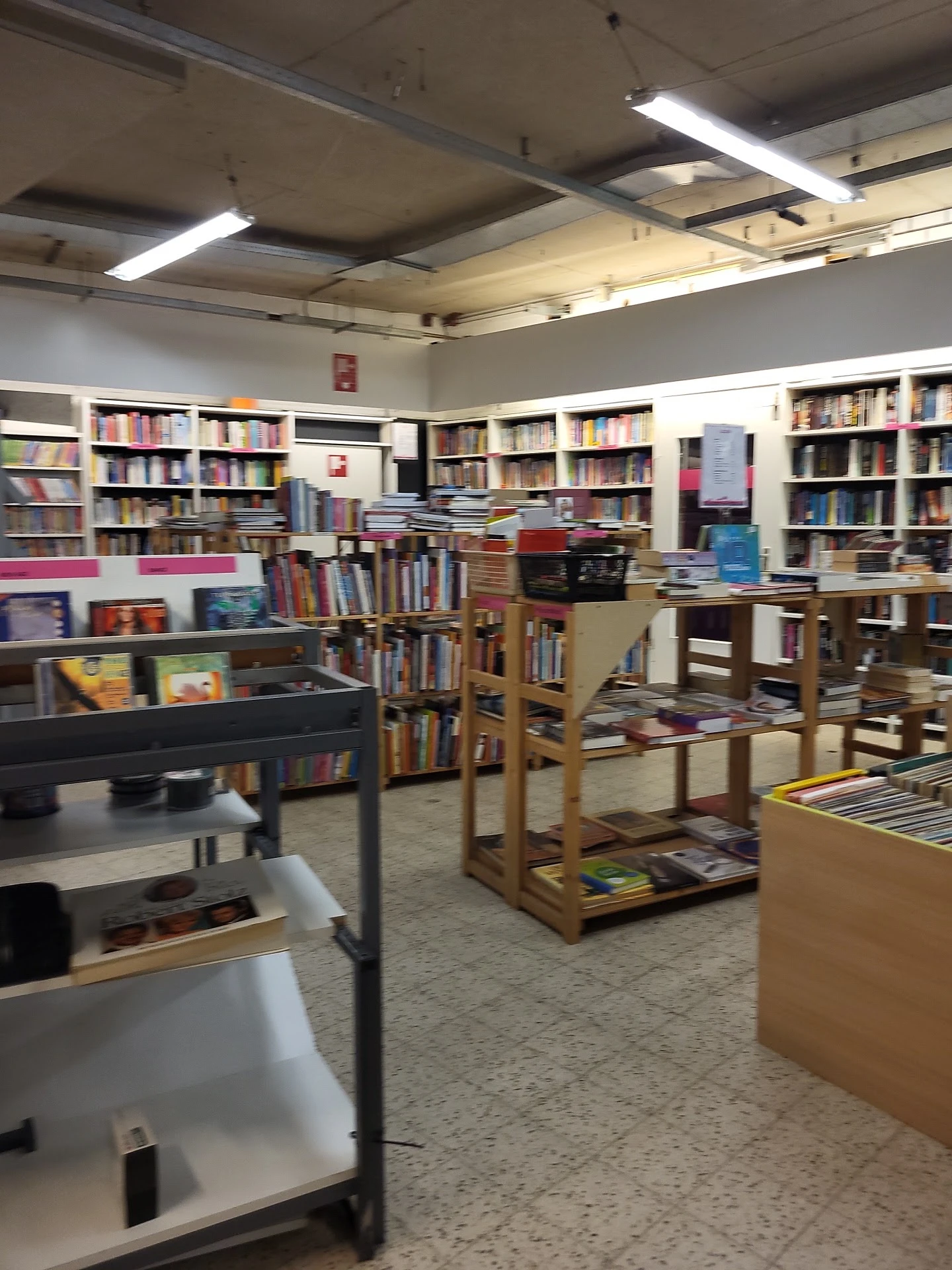 Binnenaanzicht van kringloopwinkel met boekenrekken, stellingen en diverse spullen
