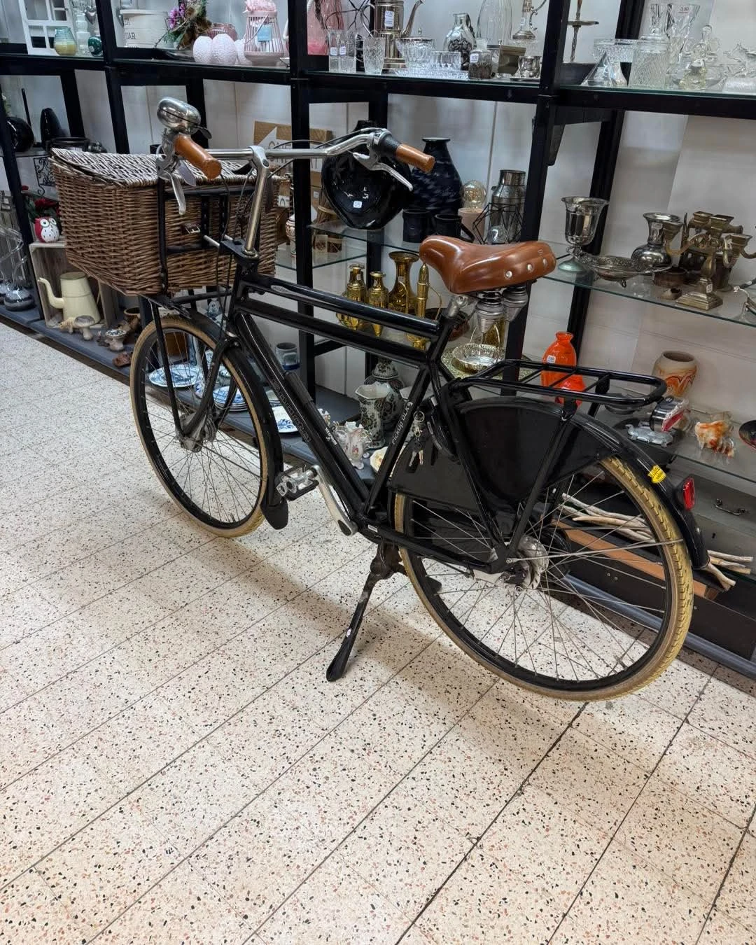Zwarte transportfiets met bruin zadel en zwarte bagagedrager, getoond in de winkel