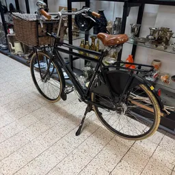 Zwarte transportfiets met bruin zadel en zwarte bagagedrager, getoond in de winkel