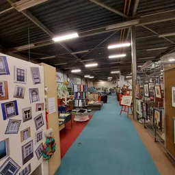 Overzicht van de winkelvloer met gekleurde looppaadjes, stellingen met boeken en diversen spullen, displayborden met ramen en