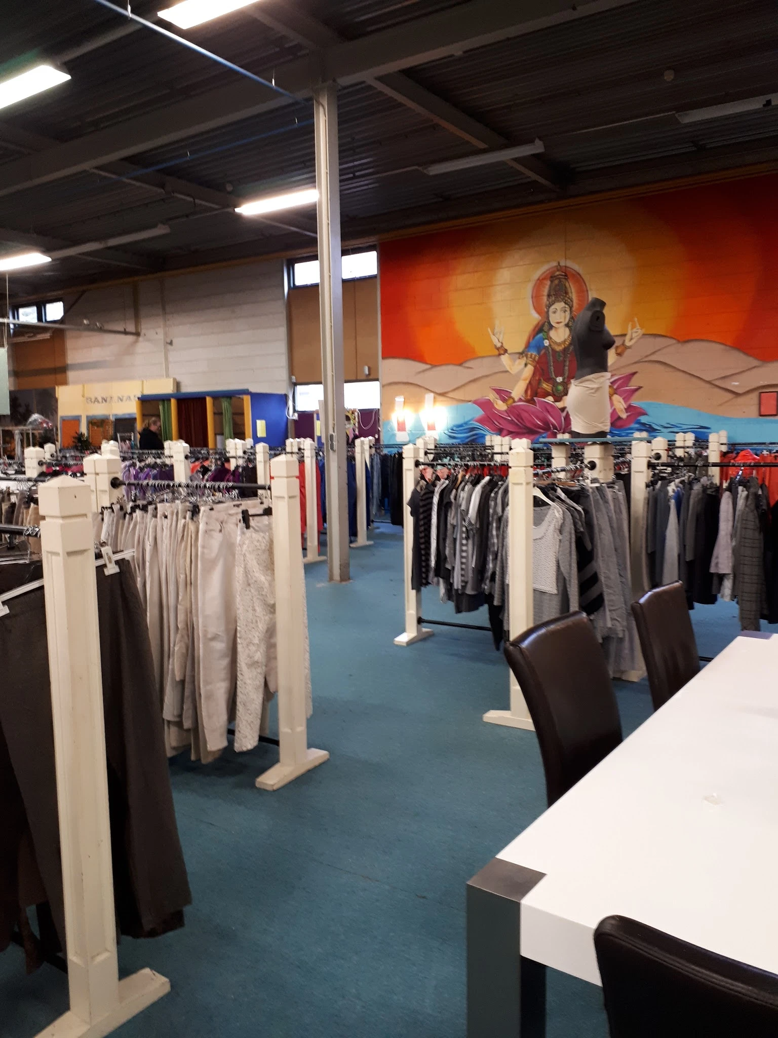 Winkelvloer met kledingrekken en decoratieve muurschildering van Hindu-godin