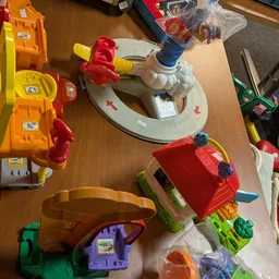 Verzameling tweedehands speelgoed inclusief voertuigen en accessoires op tafel