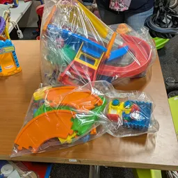 Plastic speelgoed in verpakking: gekleurde auto's en bouwstenen op tafel