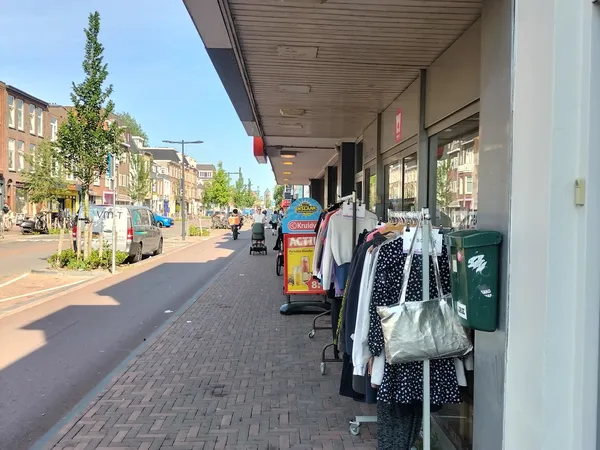 Winkelgevel met uitstallingen kleding aan het raam langs een zonnig winkelstraatje