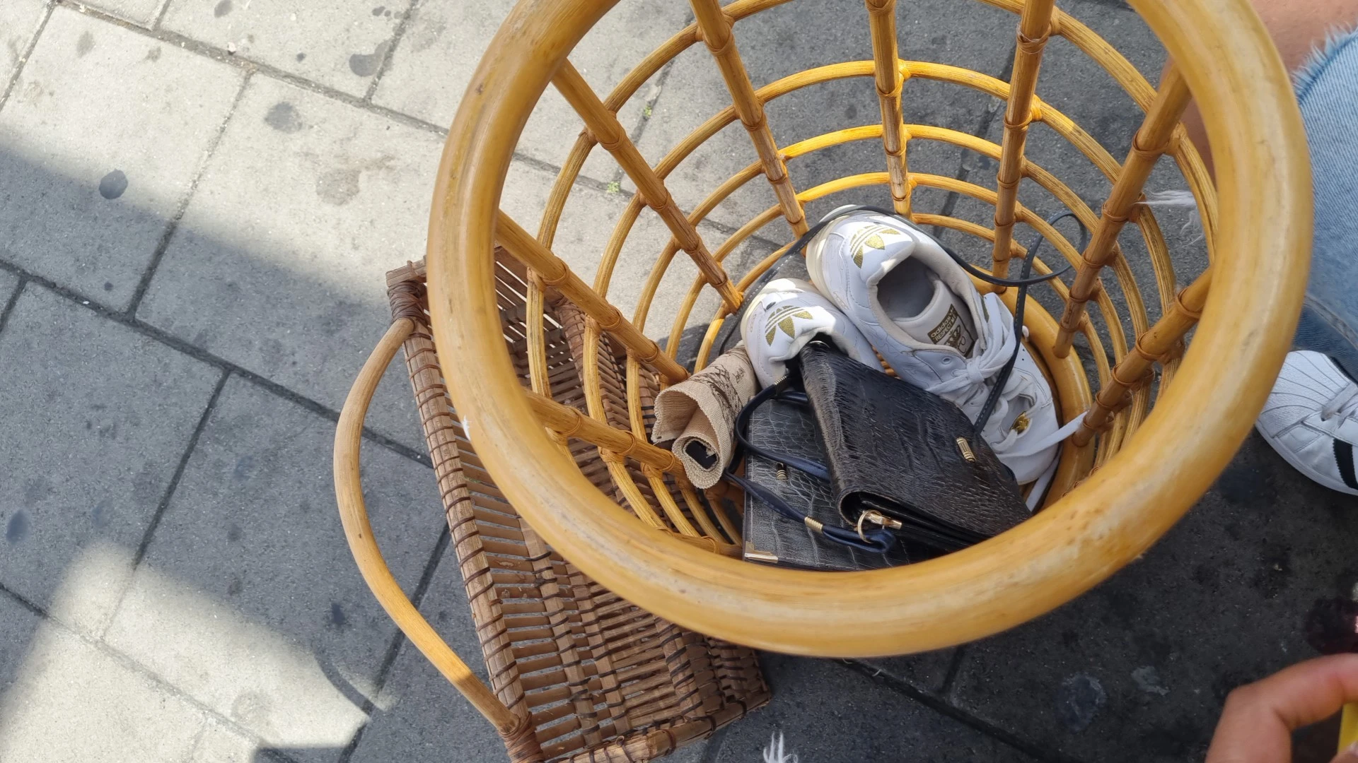 Gele rieten mand met sportschoenen en sporttas op betonnen grond