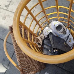 Gele rieten mand met sportschoenen en sporttas op betonnen grond