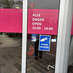 Roze gevel met openingstijden 10:00-18:00 en camerabewakingsbord