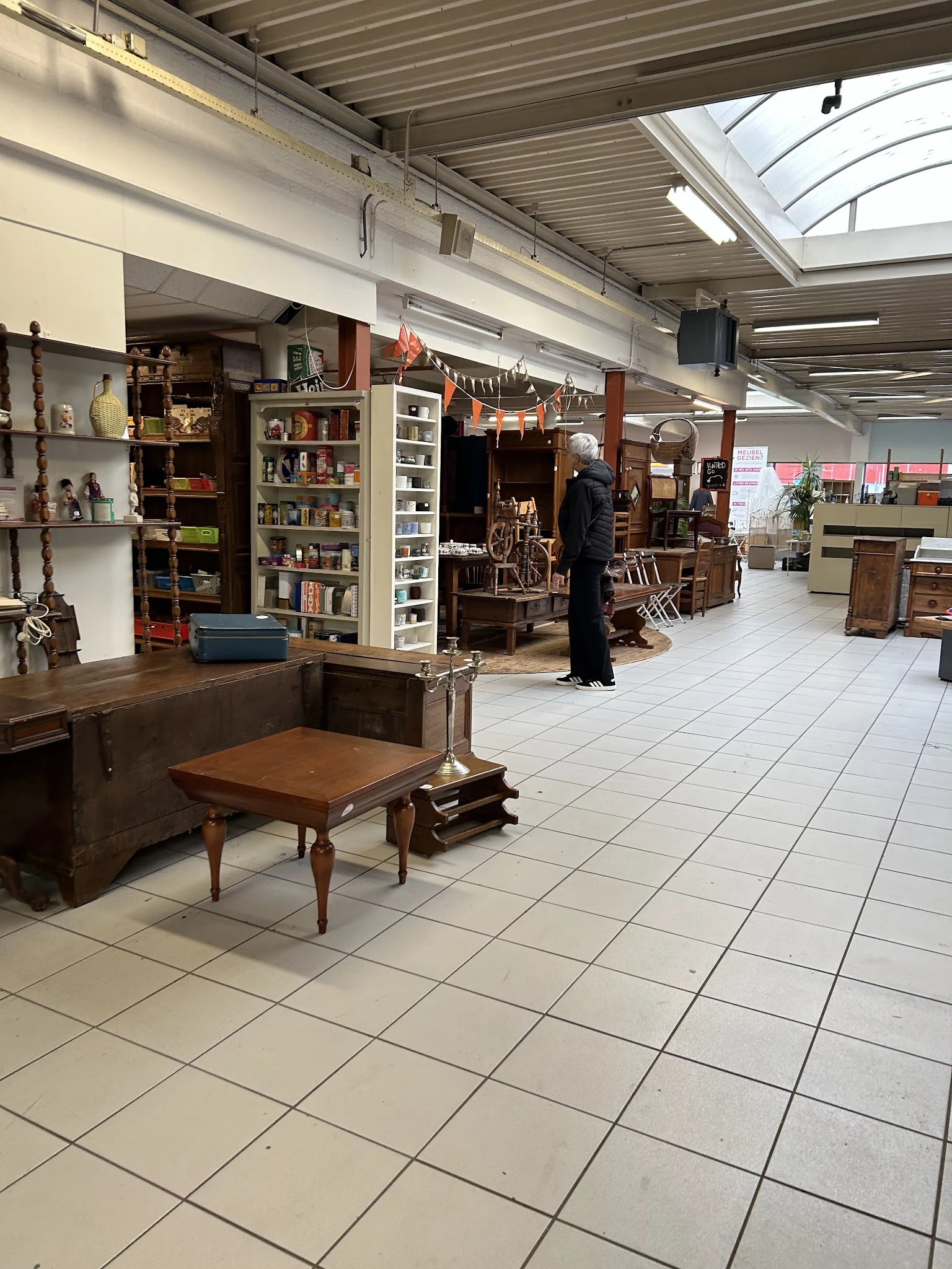 Ruim winkelinterieur met houten meubels, boeken in stellingen, decoratie en hangende ornamenten