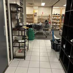 Winkelvloer van kringloopwinkel met winkelwagen, stellingen met serviesgoed en huishoudartikelen