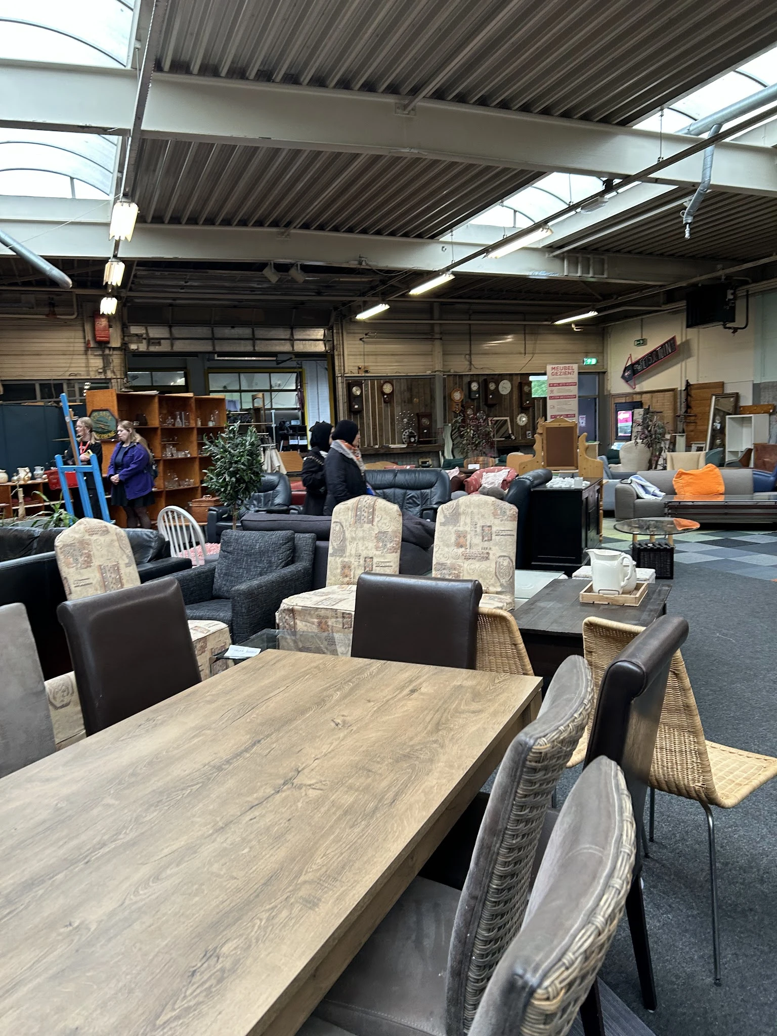 Winkelvloer met meubels zoals tafels, stoelen en kasten, bezoekers in de winkel