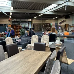 Winkelvloer met meubels zoals tafels, stoelen en kasten, bezoekers in de winkel