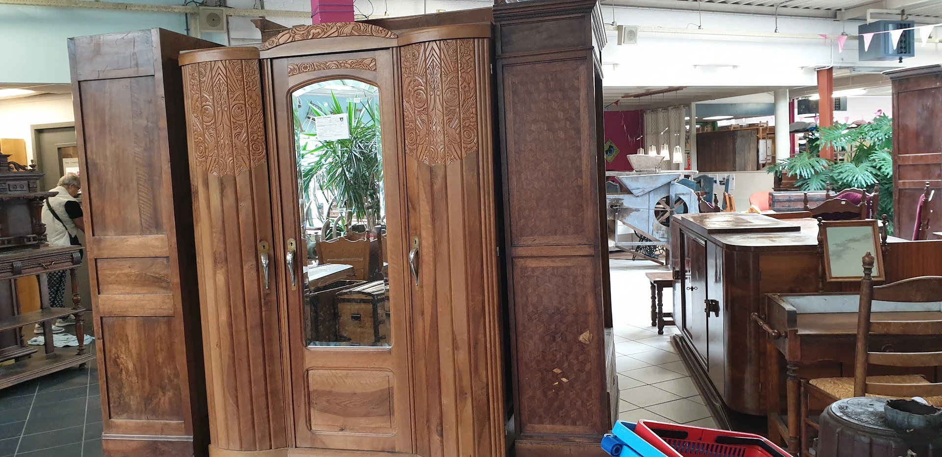 Houten kledingkast met spiegeldeuren en gebeeldhouwde details, in een kringloopwinkel