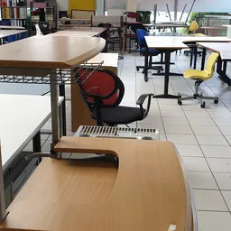 Winkelvloer met tafels, stoelen en een rode bureaustoel in een kringloopwinkel