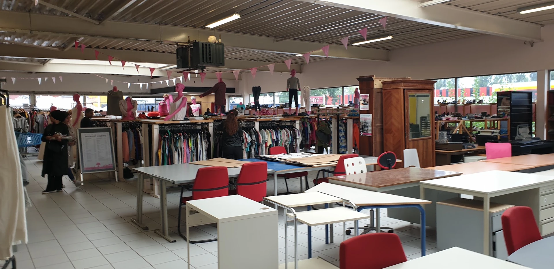 Winkelvloer met tafels, stoelen en kledingrekken met tweedehands kleding