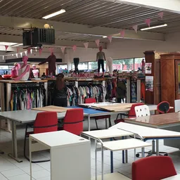 Winkelvloer met tafels, stoelen en kledingrekken met tweedehands kleding