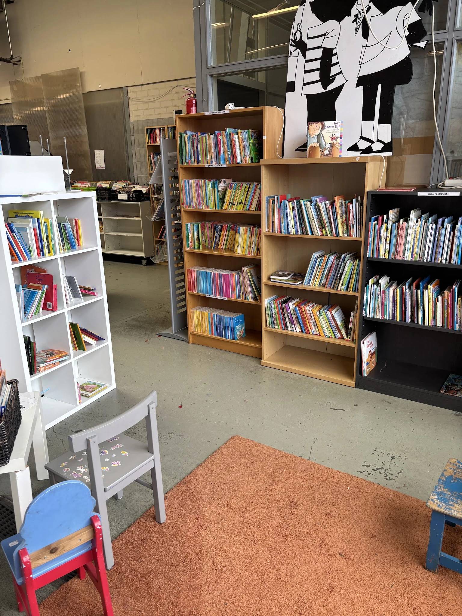 Binnenaanzicht van kringloopwinkel met meerdere boekenkasten vol DVDs en boeken langs de wanden