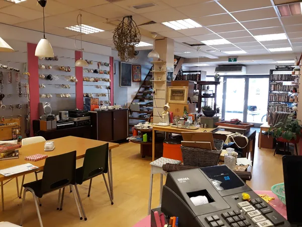 Binnenaanzicht van kringloopwinkel met diverse meubels, tafels, stoelen en uitgestalde spullen