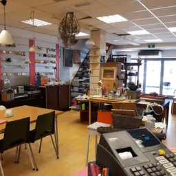 Binnenaanzicht van kringloopwinkel met diverse meubels, tafels, stoelen en uitgestalde spullen