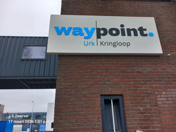 Gevel van bakstenen gebouw met wit uithangbord met blauwe Waypoint-logo en lokatie Urk Kringloop