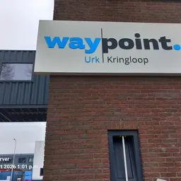 Gevel van bakstenen gebouw met wit uithangbord met blauwe Waypoint-logo en lokatie Urk Kringloop